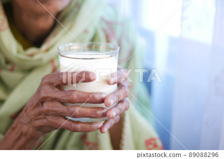 senior women hand holding a glass of milk senior women hand holding a glass of milk 89088296