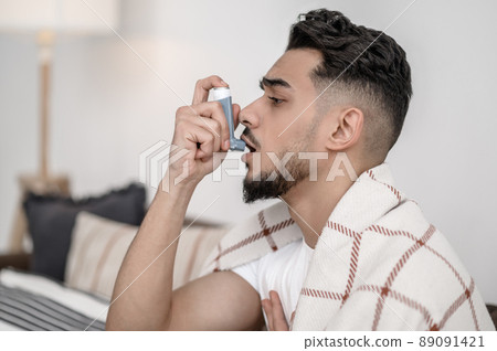 A sick man spraying nasal drops to his nose 89091421