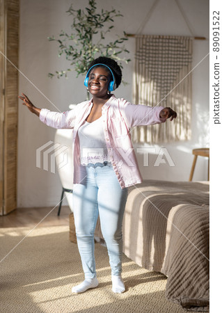 An african woman in headphones feeling joyful and dancing An african woman in headphones feeling joyful and dancing 89091522