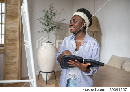 Contented african woman in light clothes near the mirror Contented african woman in light clothes near the mirror 89091567
