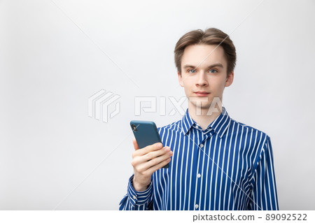 Confident young man with phone studio shot on gray background Confident young man with phone studio shot on gray background 89092522