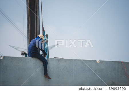 Rear view of an Asian worker working on the edge of a building at the construction site. 89093690