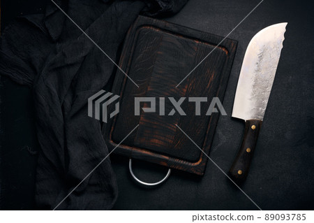 rectangular empty wooden cutting board and kitchen knife on black table with gauze napkin, top view rectangular empty wooden cutting board and kitchen knife on black table with gauze napkin, top view 89093785