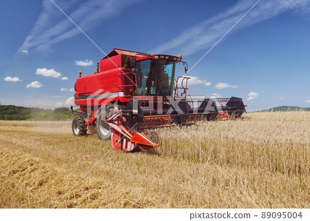 Red harvester harvesting grain on field Red harvester harvesting grain on field 89095004