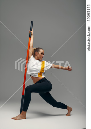 beautiful girl in sports uniform is training kung fu in the studio, fighter athlete, practicing martial arts with a stick beautiful girl in sports uniform is training kung fu in the studio, fighter athlete, practicing martial arts with a stick 89095153