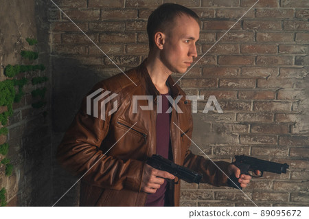 young guy with gun in leather jacket in profile young guy with gun in leather jacket in profile 89095672
