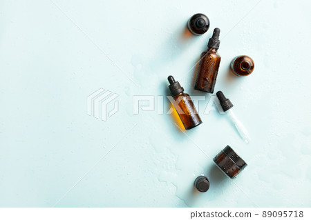 Amber glass cosmetic bottles mockups with water drops on blue background. Natural organic beauty product packaging design. Amber glass cosmetic bottles mockups with water drops on blue background. Natural organic beauty product packaging design. 89095718