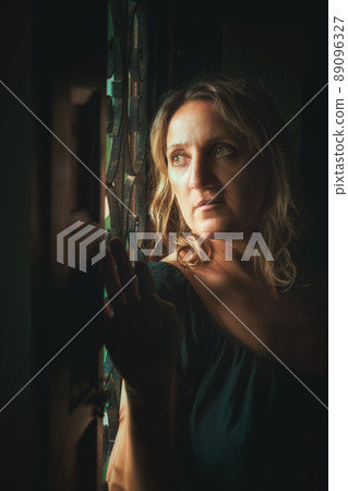a young woman stands at the window a young woman stands at the window 89096327