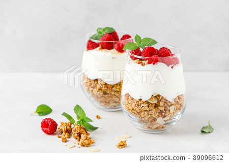 Granola with white plain yogurt and raspberry in a glass Granola with white plain yogurt and raspberry in a glass 89096612