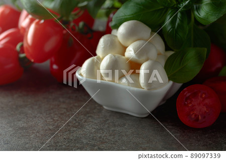 Mozzarella cheese with basil and tomatoes on an old stone table. Mozzarella cheese with basil and tomatoes on an old stone table. 89097339
