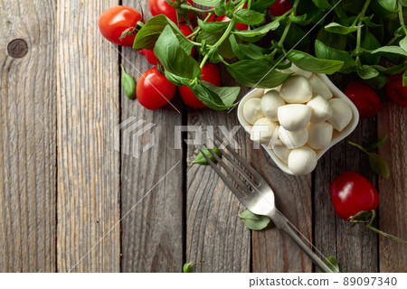 Mozzarella cheese with basil and tomatoes on an old wooden table. Mozzarella cheese with basil and tomatoes on an old wooden table. 89097340