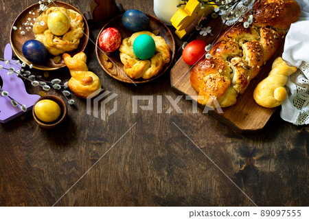 Easter holiday table. Easter cakes and colored eggs on a wooden table. Top view flat lay background. Copy space. 89097555