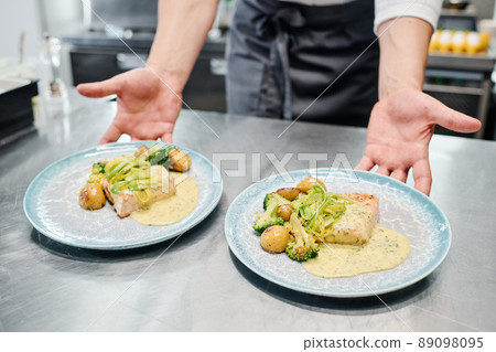 Close-up of chef putting plates with ready dish on kitchen counter for delivery Close-up of chef putting plates with ready dish on kitchen counter for delivery 89098095