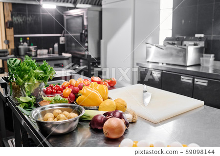 Image of workplace of chef with cutting board and fresh vegetables in commercial kitchen 89098144
