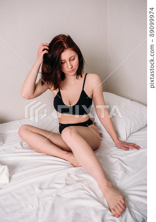Portrait of a young beautiful brunette lying in bed wearing underwear 89099974