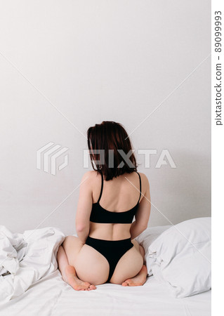 Portrait of a young beautiful brunette lying in bed wearing underwear 89099993