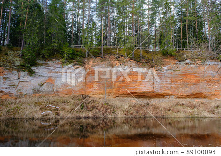 The Echo cliff near river Salaca in Mazsalaca nature park. Beautiful natural formation. A naturally formed cave in the sandstone rock. A river flows along the cave. Devonian period. 89100093