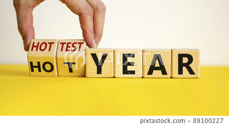 Hottest year and global warming concept. Hand turns cubes and changes words 'hot year' to 'hottest year'. Beautiful yellow table, white background. Business and hottest year concept. Copy space. Hottest year and global warming concept. Hand turns cubes and changes words 'hot year' to 'hottest year'. Beautiful yellow table, white background. Business and hottest year concept. Copy space. 89100227