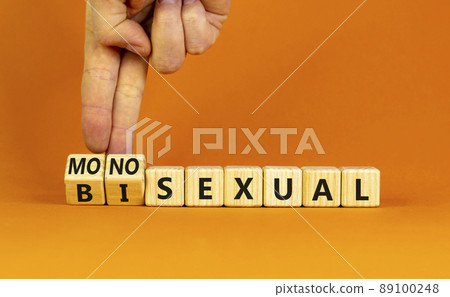 Monosexual or bisexual symbol. Doctor turns wooden cubes and changes the word 'monosexual' to 'bisexual'. Beautiful orange background, copy space. Social, monosexual or bisexual concept. Monosexual or bisexual symbol. Doctor turns wooden cubes and changes the word 'monosexual' to 'bisexual'. Beautiful orange background, copy space. Social, monosexual or bisexual concept. 89100248