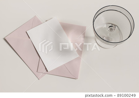Modern summer stationery still life. Champagne, cocktail glass with long shadows. Blush pink envelopes, blank greeting card mock up scene. Beige table background in sunlight. Flat lay, top view. Modern summer stationery still life. Champagne, cocktail glass with long shadows. Blush pink envelopes, blank greeting card mock up scene. Beige table background in sunlight. Flat lay, top view. 89100249