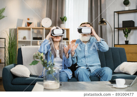 Happy mature family playing games at home and using VR glasses at home. Happy mature family playing games at home and using VR glasses at home. 89100477