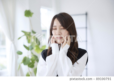 A woman who has a toothache and holds her cheeks 89100791