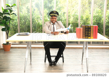 An African male flight attendant poses at his desk in the workplace. An African male flight attendant poses at his desk in the workplace. 89100820