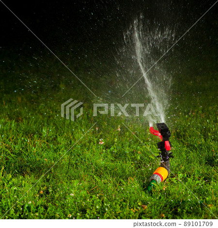 lawn sprinkler spraying water over green grass at night lawn sprinkler spraying water over green grass at night 89101709