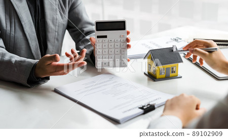Sales manager or real estate agent show calculator for total price for buying a new house to customer. Sales manager or real estate agent show calculator for total price for buying a new house to customer. 89102909