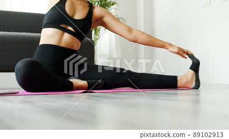 Pretty Asian woman doing yoga exercise stretching online class from laptop at home in living room. Pretty Asian woman doing yoga exercise stretching online class from laptop at home in living room. 89102913