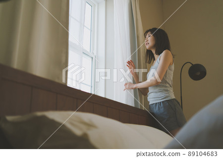 Woman looking out the window in the morning 89104683