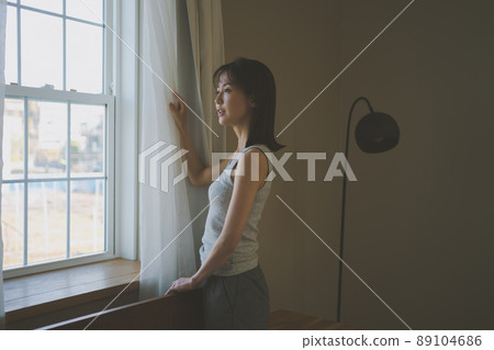 Woman looking out the window in the morning 89104686
