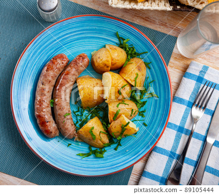 Fried sausages served with baked potatoes and greens 89105444