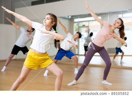 Smiling teenage girl enjoying active dance with family in studio Smiling teenage girl enjoying active dance with family in studio 89105852