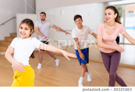 Smiling teenage girl enjoying active dance with family in studio 89105863