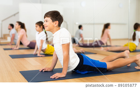 Boy doing cobra pose during family yoga training 89105877