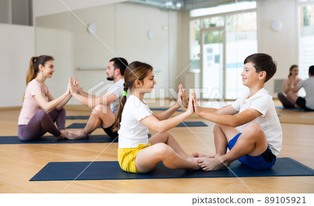 Mother and kid daughter in the gym centre doing yoga poses or stretching  fitness exercise near