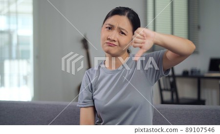 Asian woman annoyed and showing thumb down. Asian woman annoyed and showing thumb down. 89107546
