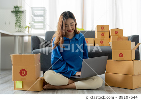Startup SME small business entrepreneur, holding card box standing at her home office. Beautiful success Asian businesswoman online marketing, SME preparing package parcel delivery to her customer 89107644