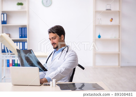 Young male doctor in wheel-chair working in the clinic Young male doctor in wheel-chair working in the clinic 89108481