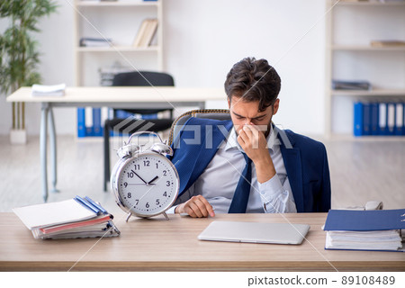 Young male employee in time management concept Young male employee in time management concept 89108489
