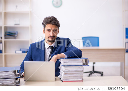 Young male employee and too much work in the office 89108504