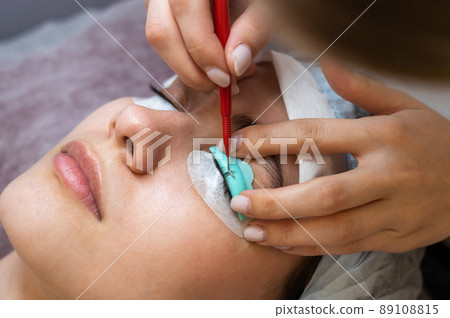 Young woman undergoing eyelash tinting and lamination procedure. 89108815