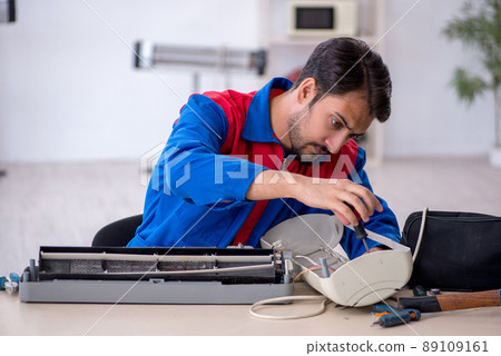 Young male repairman repairing air-conditioner Young male repairman repairing air-conditioner 89109161