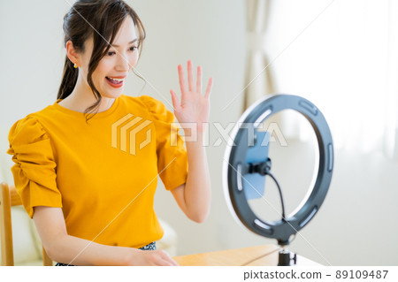 A woman in her twenties waving to her followers in a video distribution 89109487
