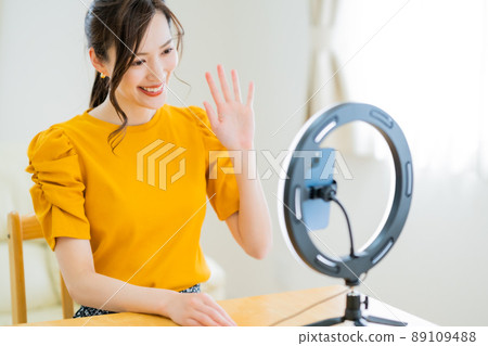 A woman in her twenties waving to her followers in a video distribution 89109488