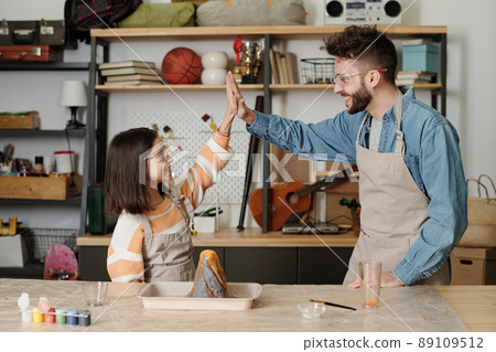 Happy child and man making high-five by table with erupting handmade volcano Happy child and man making high-five by table with erupting handmade volcano 89109512