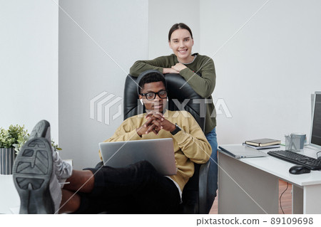 Young intercultural programmers in casualwear looking at camera by workplace 89109698