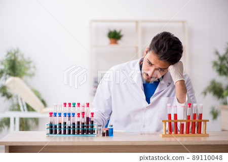Young male biochemist testing blood samples in pandemic concept 89110048