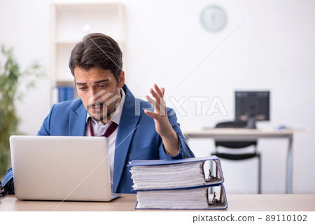 Young male employee unhappy with excessive work in the office 89110102